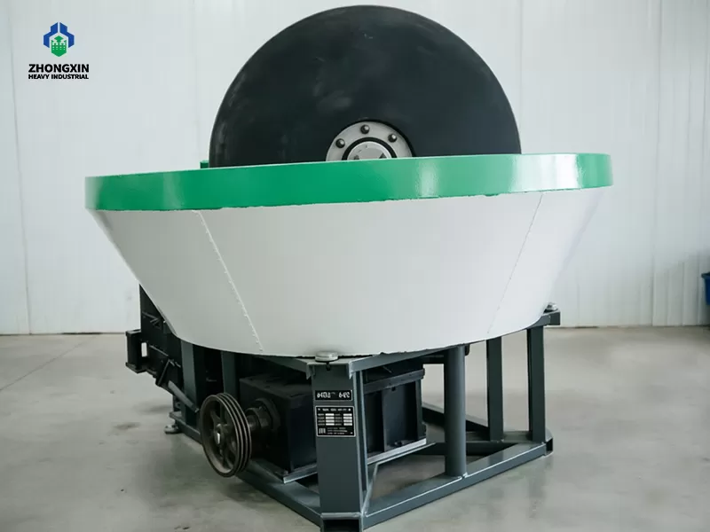 Heavy-duty cast iron rollers and grinding basin inside wet pan mill workshop
